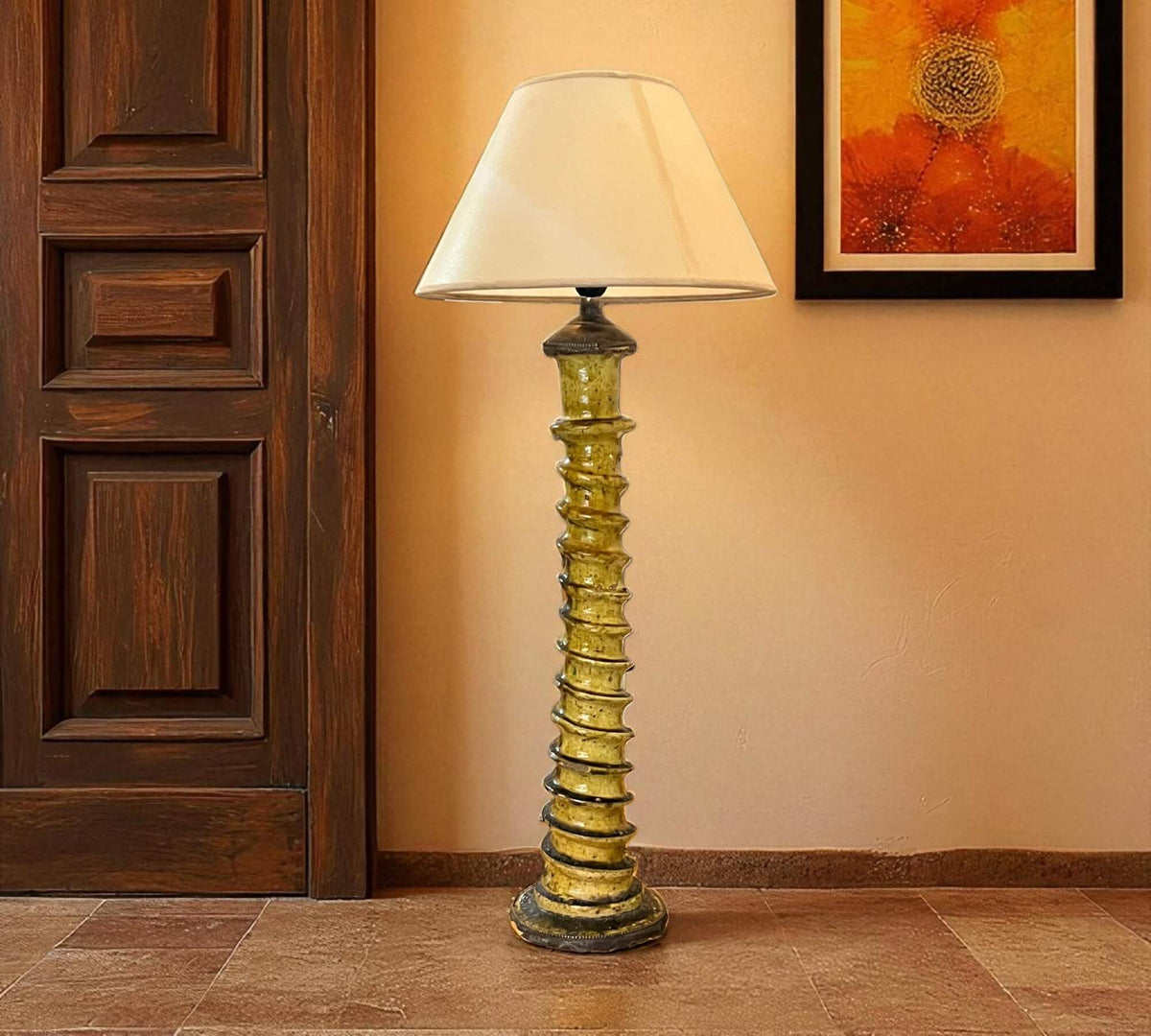 Decorative floor lamp with a textured base in a room with wooden door and wall art.
