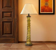Decorative floor lamp with a textured base in a room with wooden door and wall art.