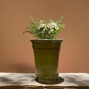 Vintage-style yellow pot with flowers on a wooden surface against a brown background