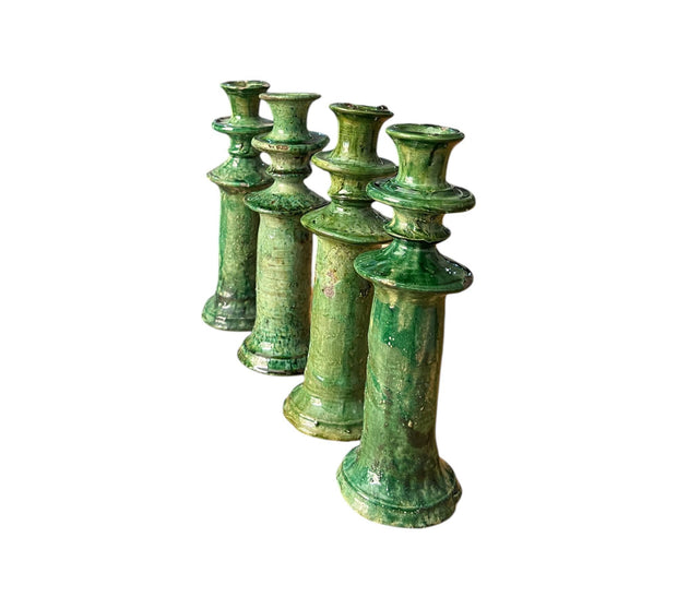 Set of six green ceramic candle holders on a white background