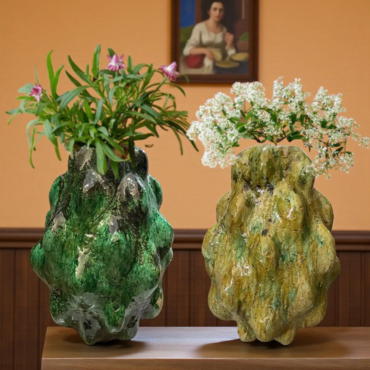 Two unique, textured vases with plants on a wooden surface against an orange wall.