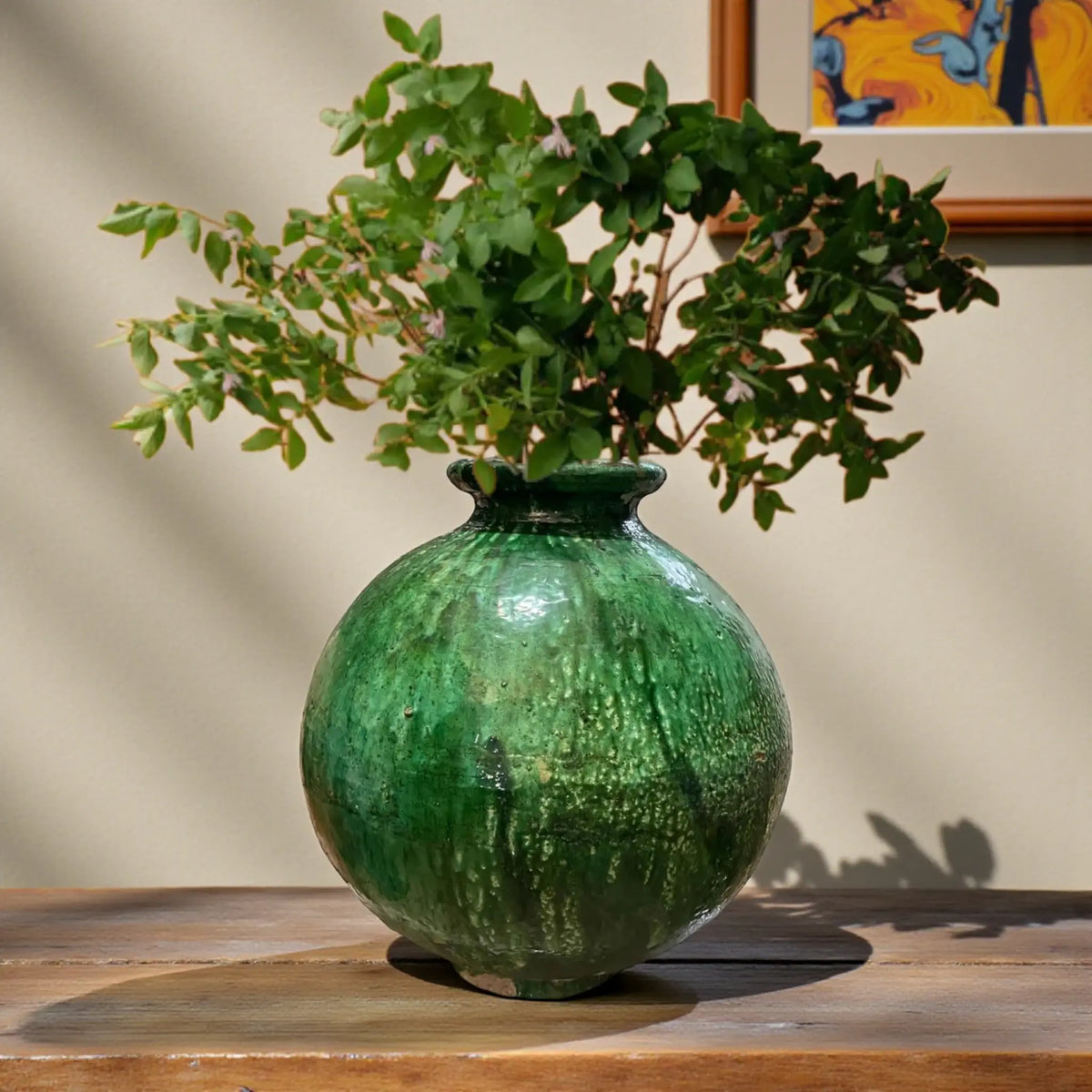 Large rounded handmade Tamegroute pottery vase with deep green kiln glaze on wooden table
