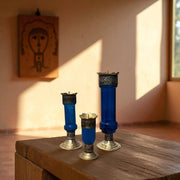Vintage hand‑engraved silver‑plated brass and recycled glass candlesticks on a wooden surface with a warm light setting.