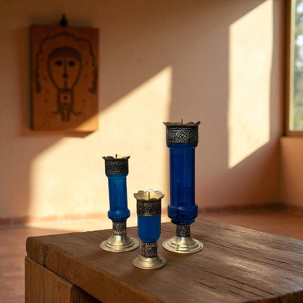 Vintage hand‑engraved silver‑plated brass and recycled glass candlesticks on a wooden surface with a warm light setting.