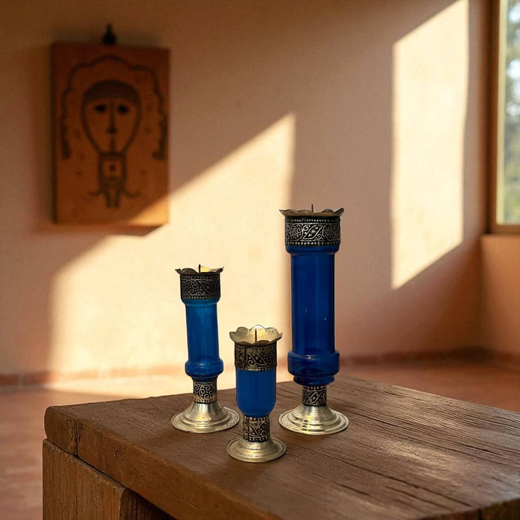 Vintage hand‑engraved silver‑plated brass and recycled glass candlesticks on a wooden surface with a warm light setting.