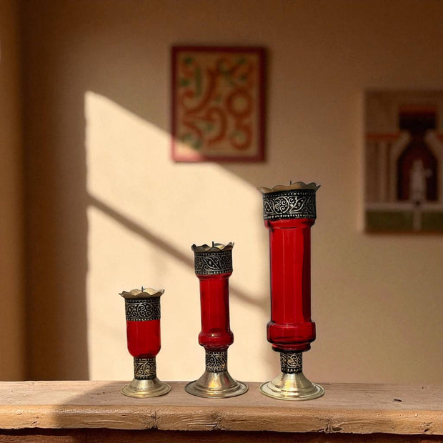 Vintage hand‑engraved silver‑plated brass and recycled glass candlesticks on a wooden surface, with a blurred background.