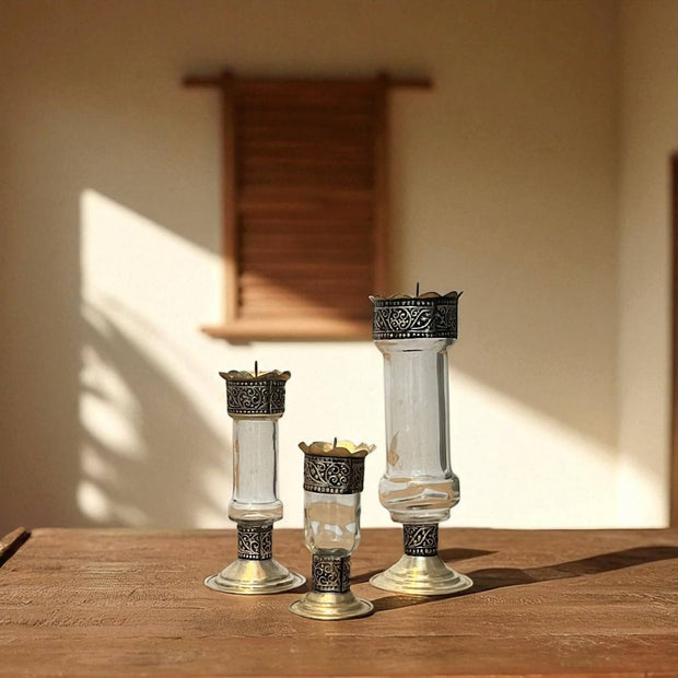 Vintage hand‑engraved silver‑plated brass and recycled glass candlesticks  on a wooden surface with a warm background