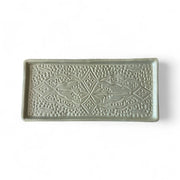 Decorative rectangular tile with intricate patterns on a white background