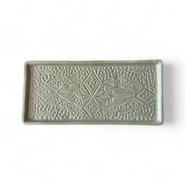 Decorative rectangular tile with intricate patterns on a white background