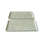 Two green ceramic trays with decorative patterns on a white background