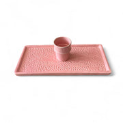 Pink tray with embossed design and matching cup on a white background