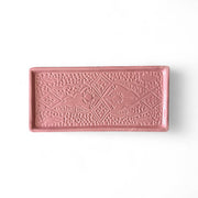 Pink ceramic tray with decorative patterns on a white background