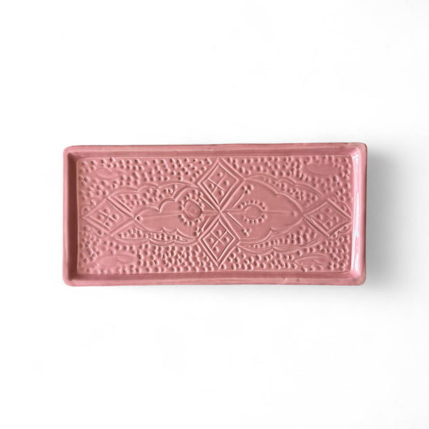 Pink ceramic tray with decorative patterns on a white background