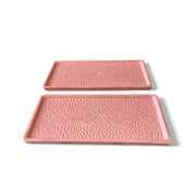 Two pink trays with decorative patterns on a white background