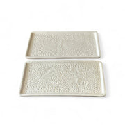 Two white ceramic trays with decorative patterns on a white background
