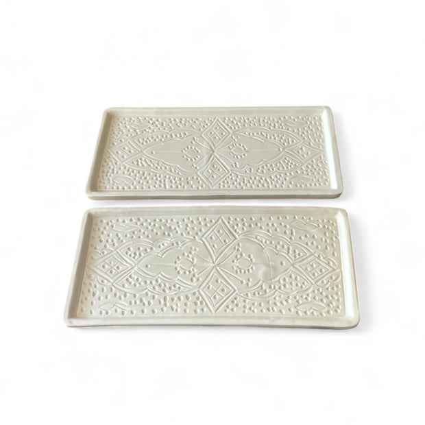 Two white ceramic trays with decorative patterns on a white background