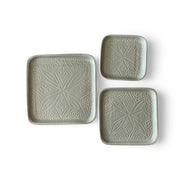 Set of three square ceramic plates with textured patterns on a white background