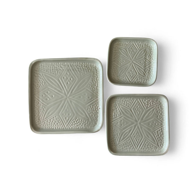 Set of three square ceramic plates with textured patterns on a white background