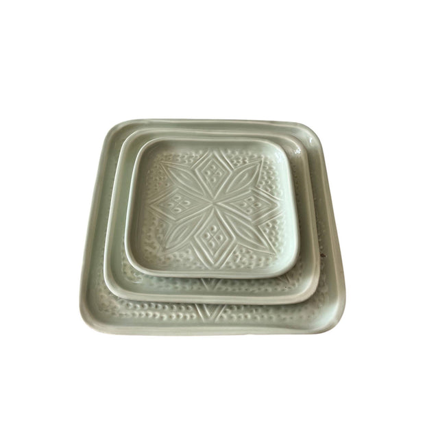 Set of two square ceramic trays with embossed designs on a white background