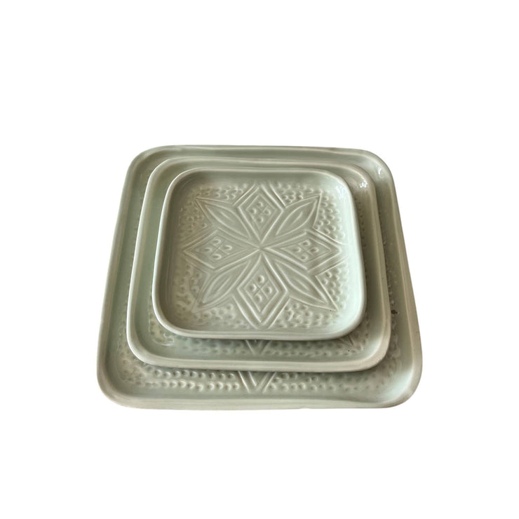 Set of two square ceramic trays with embossed designs on a white background