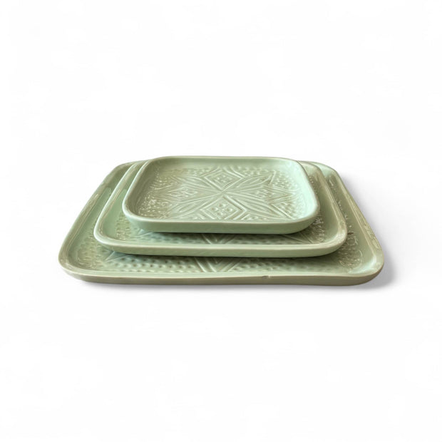 Set of three green ceramic trays with geometric patterns on a white background