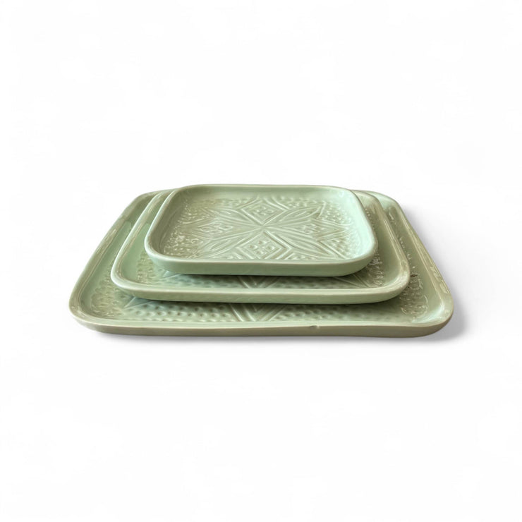 Set of three green ceramic trays with geometric patterns on a white background