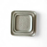 Square ceramic dish with decorative pattern on a white background