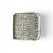 Green ceramic square plate with textured pattern on a white background