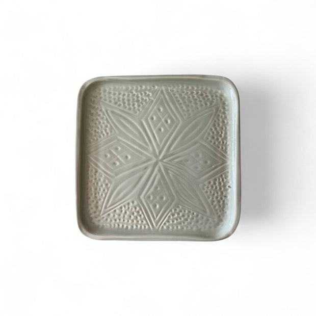 Green ceramic square plate with textured pattern on a white background