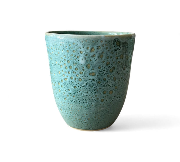 Turquoise ceramic cup with speckled pattern on a white background