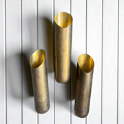 Three brass wall sconces on a white wooden panel background