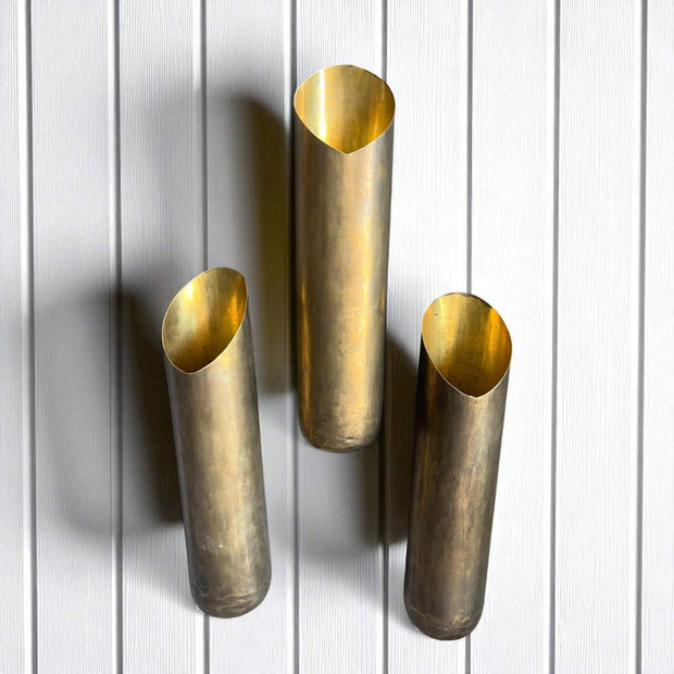 Three brass wall sconces on a white wooden panel background